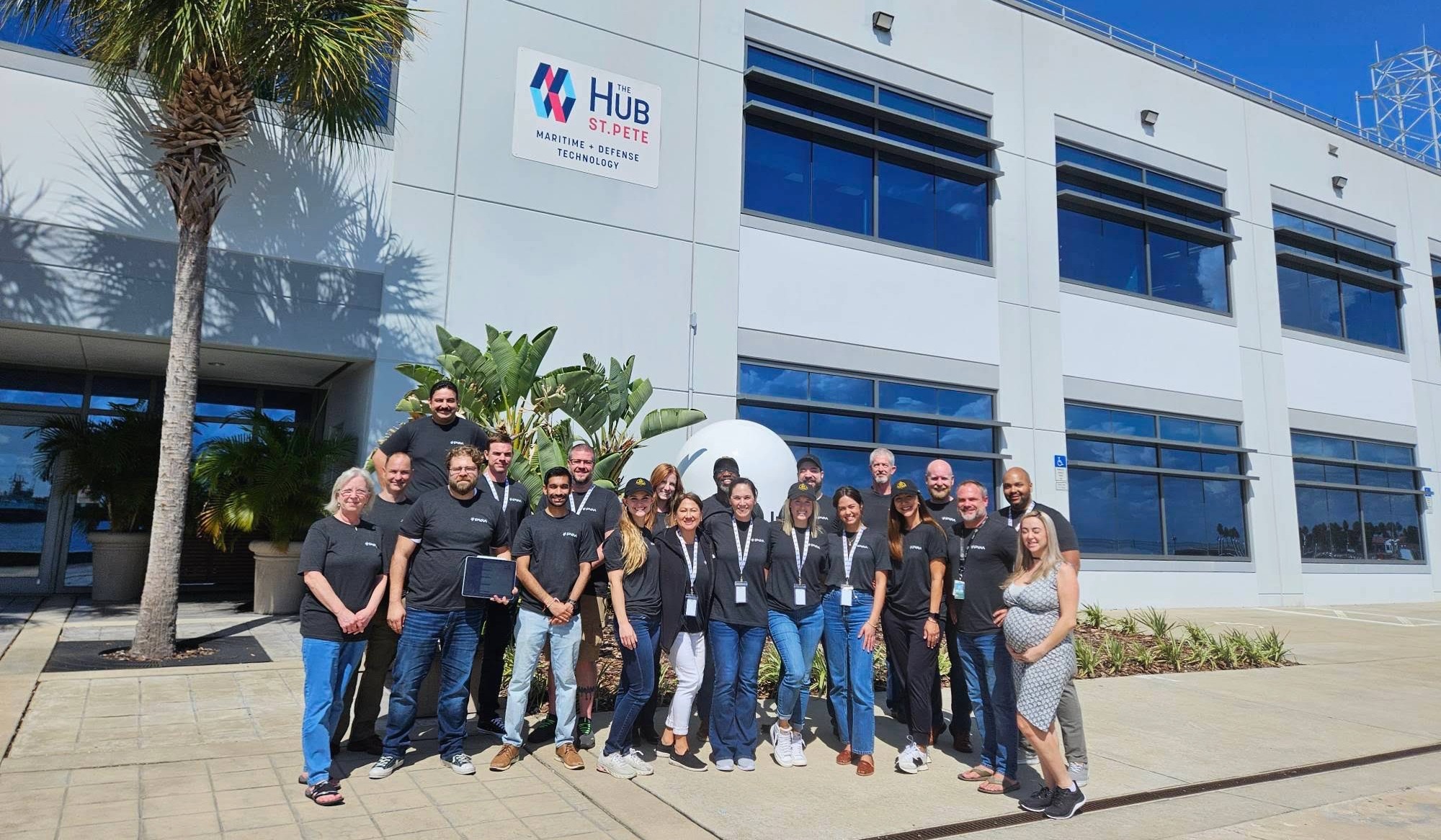 a group photo outside of a building with a sign that reads Hub St. Pete